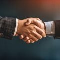 Two business professionals engage in a handshake, symbolizing partnership and collaboration. This gesture represents trust and agreement in a corporate environment.