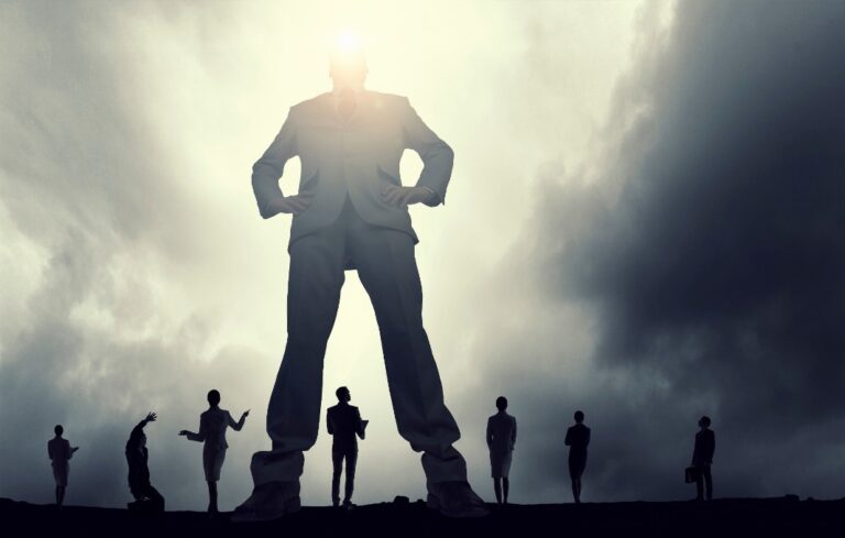Giant person in business suit standing over smaller business people at his feet