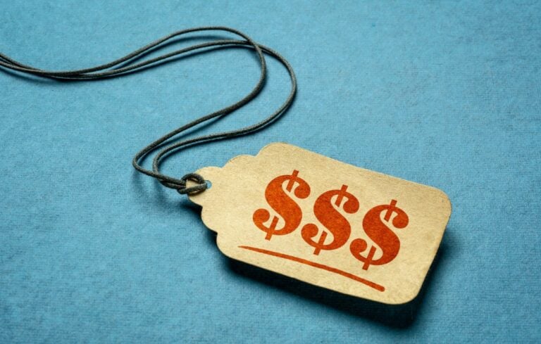 triple dollar sign - red stencil text on a paper price tag against blue paper background
